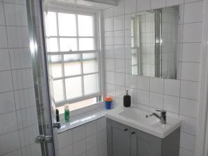 baño con lavabo, espejo y ventana en The Coach House, Hesket Newmarket en Hesket Newmarket