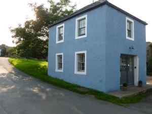 una casa azul al lado de una calle en The Coach House, Hesket Newmarket en Hesket Newmarket