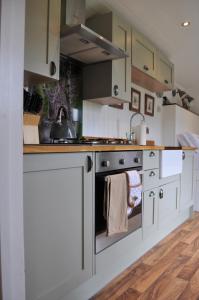 a kitchen with white cabinets and an oven at Fullabrook Farm Retreat, The Shepherdess Hut in West Down