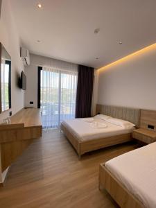 a bedroom with two beds and a large window at GL Hotel Ksamil in Ksamil