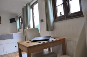 a desk with a laptop on it in a room at Fullabrook Farm Retreat, The Shepherdess Hut in West Down