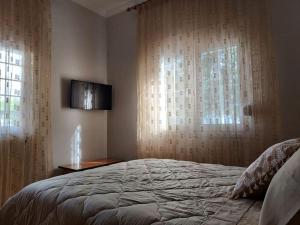 1 dormitorio con 1 cama y una ventana con cortinas en Aggeliki's place detached home with yard/parking, en Volos