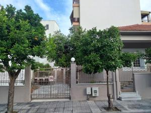 una valla con dos árboles frente a un edificio en Aggeliki's place detached home with yard/parking, en Volos
