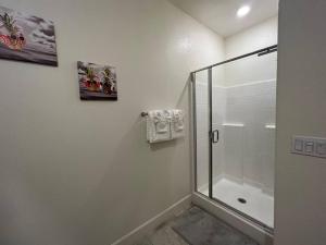 Baño blanco con ducha con puerta de cristal en Brand-New, Beautiful & Stylish Home in Sacramento!, en Sacramento