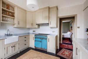 a kitchen with white cabinets and a blue stove top oven at Church view apartment in Drewsteignton