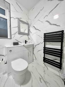 a white bathroom with a toilet and a marble wall at Home in the Heart of Manchester in Manchester
