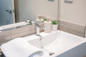 lavabo blanco con grifo y espejo en Molly's Little Apartments, en Melbourne