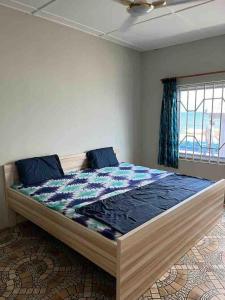 a bedroom with a large bed with blue sheets at Anne’s Beach House in Nyanyanu