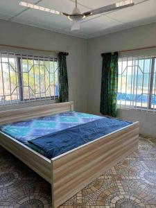 Cette chambre comprend un grand lit et des fenêtres. dans l'établissement Anne’s Beach House, à Nyanyanu