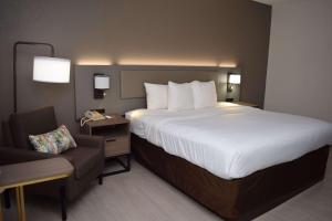 una habitación de hotel con una cama grande y una silla en Comfort Inn & Suites Syracuse-Carrier Circle, en East Syracuse