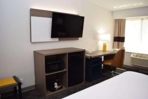um quarto de hotel com uma secretária e uma televisão na parede em Comfort Inn & Suites Syracuse-Carrier Circle em East Syracuse