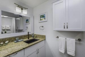 a white bathroom with a sink and a mirror at Sandpiper 216B condo in Princeville