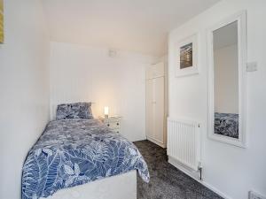 Schlafzimmer mit einem Bett mit einer blauen und weißen Bettdecke in der Unterkunft Stable Cottage - Uk10694 in Amroth