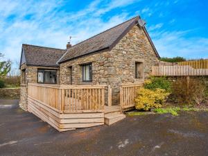 een stenen huis met een houten terras en een hek bij Stable Cottage - Uk10694 in Amroth