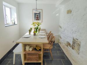 a dining room with a wooden table and chairs at Churchtown Cottage in Cubert