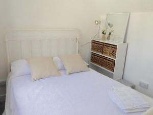 a white bed with two pillows and a mirror at Churchtown Cottage in Cubert