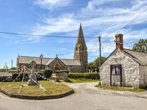an old stone church with a cross in front of it at Churchtown Cottage in Cubert