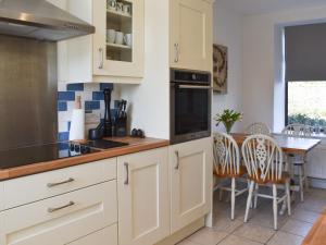 una cucina con armadi bianchi e tavolo con sedie di Ty Newydd a Llandwrog