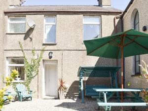 una panchina verde e un ombrello davanti a una casa di Ty Newydd a Llandwrog