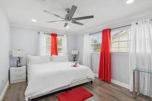 biała sypialnia z białym łóżkiem i czerwonymi zasłonami w obiekcie Stunning Miami Oasis with Private Furnished Patio! w mieście Miami Gardens
