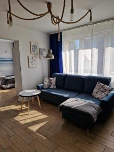 赫爾的住宿－Przystań Hel Apartament，客厅配有蓝色的沙发和桌子