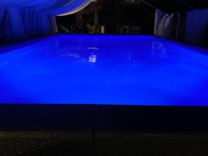 a large blue swimming pool at night at Mini Love Island style guest house with a hot private swimming pool and heated dining pod, secretly located in the busy suburbs of Nottingham in Nottingham