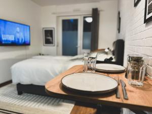 a table with two plates and glasses and a bed at Modernes Wohlfühl-Apartment an den Kaiserthermen in Trier
