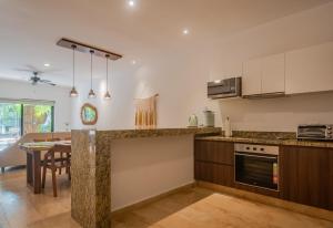 a kitchen with a counter and a dining room at Luxury Aldea Zama 2bed - 2bat Apartment Private Terrace & Swim Up in Tulum