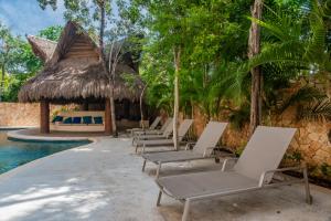 eine Reihe von Chaiselongues neben einem Pool in der Unterkunft Luxury Aldea Zama 2bed - 2bat Apartment Private Terrace & Swim Up in Tulum