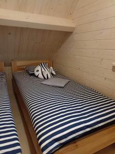 two bunk beds in a room with a striped bed at Domki Anielski Zakątek J&R nad Bałtykiem DELUX z klimatyzacją in Mielenko