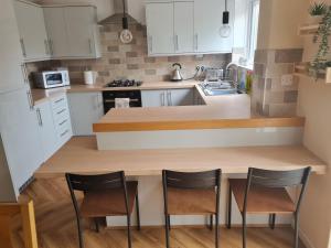 a kitchen with white cabinets and two chairs at a counter at Crabtree House in Moreton