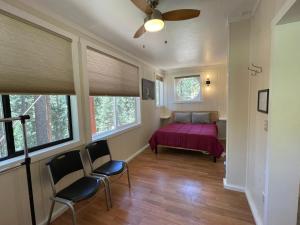 a bedroom with a bed and two chairs and windows at Chalet Yosemite in Yosemite West