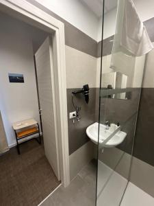La salle de bains est pourvue d'un lavabo et d'une douche en verre. dans l'établissement M&M rooms Margherita di Savoia, à Margherita di Savoia