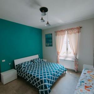 een blauwe slaapkamer met een bed en een raam bij Villa immersa nelle colline toscane, vista vigneto in Cortona