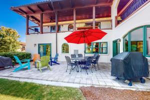 een patio met een tafel en stoelen en een rode parasol bij Abruzzi - Villa B in Eatonton 