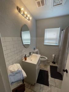 a bathroom with a sink and a toilet and a mirror at Quiet Comfort minutes from BOK and downtown Tulsa in Tulsa
