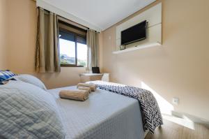 a bedroom with a bed with a tv on the wall at apartamentos Coração Eucarístico in Belo Horizonte