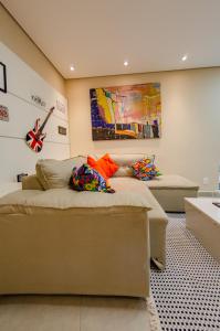 a room with a couch and a guitar on the wall at apartamentos Coração Eucarístico in Belo Horizonte