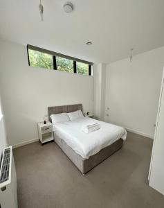 a white bedroom with a bed and a window at Luxury Modern 1 Bed Apartment in London