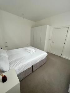 a white bedroom with a bed and a table at Luxury Modern 1 Bed Apartment in London