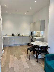 Luxury Modern 1 Bed Apartment في لندن: مطبخ مع طاولة وطاولة وكراسي