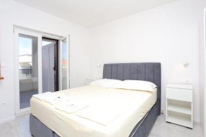 ein weißes Schlafzimmer mit einem großen Bett und einem Fenster in der Unterkunft Apartment Baska Voda 6773a in Baška Voda