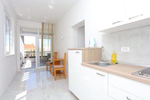eine weiße Küche mit einem Waschbecken und einem Tisch in der Unterkunft Apartment Baska Voda 6773a in Baška Voda