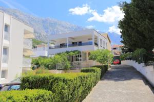 a white building with a hedge in front of it at Apartments with parking space Baska Voda, Makarska - 6773 in Baška Voda
