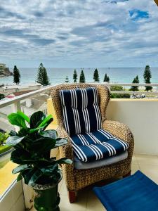 a wicker chair sitting on a balcony overlooking the ocean at SeaDreams Beachfront Manly in Manly 