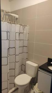 y baño con aseo y cortina de ducha. en Departamento en Villa Elisa., en Villa Elisa