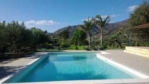 una piscina en un patio con montañas al fondo en Taormina Villa Ibiscus Alcantara, en Gaggi