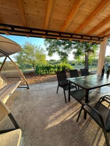 a patio with a table and chairs under a wooden roof at Relax and Unwind: Family-Friendly House near Zadar in Zagrad in Zadar