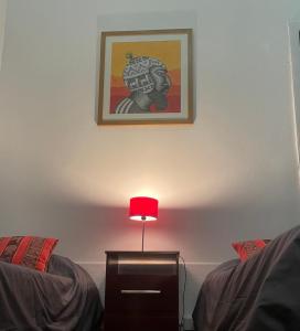 una mesa con una lámpara roja junto a 2 camas en Andino BnB en Salta