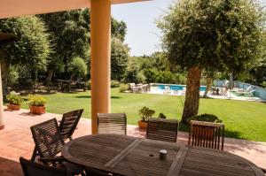 a wooden table and chairs on a patio with a pool at Sotogrande - Estancia en plena naturaleza - Abril in Sotogrande